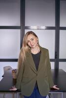 blond femme avec longue cheveux dans une vert veste et jeans dans le Bureau photo