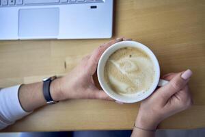 femelle mains tenir une tasse de café sur le tableau, portable suivant à il photo