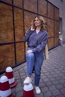 élégant femme posant mine de rien sur circulation cônes à l'extérieur Urbain bâtiment à crépuscule photo