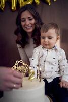 émotif Parents regarder comme leur fils coups en dehors le bougies sur le anniversaire gâteau photo