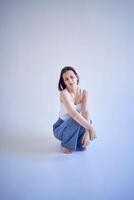 Jeune adolescent fille est assis sur une blanc cyclorama dans le studio photo