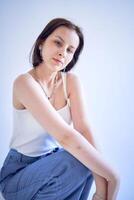 Jeune adolescent fille est assis sur une blanc cyclorama dans le studio photo