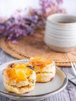 fermer de traditionnel Britanique scones sur une assiette avec une tasse de thé et fleur flou Contexte. espace pour texte photo