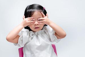 petite fille lorgnant à travers sa main avec un œil. sur fond blanc isolé. maternelle 4-5 ans. photo