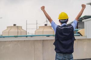 un ingénieur debout sur le toit du bâtiment de production montre son engagement et son succès