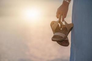 femme tenant des sandales marchant sur la plage photo