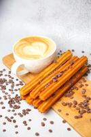 cappuccino et churro des bâtons sur une Coupe planche photo