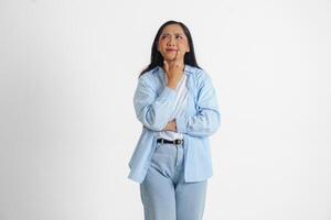 une réfléchi asiatique femme portant bleu chemise est imaginer sa pensées, isolé par blanc Contexte. photo