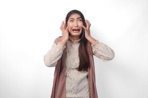 un asiatique musulman femme élevage tous les deux mains à tenir sa tête sentiment stressé et dépassé, pleurs et en hurlant désespérément, isolé blanc Contexte photo