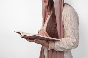 proche en haut portrait de asiatique musulman femme dans foulard voile hijab en portant et en train de lire Al coran plus de isolé blanc Contexte. Ramadan et eid mubarak concept. photo