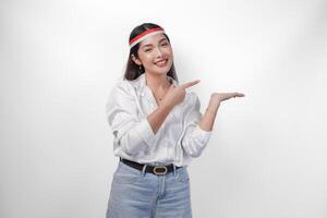 excité asiatique femme portant drapeau Bandeau en présentant et montrer du doigt à le copie espace sur le côté, souriant large et permanent sur isolé blanc Contexte. indépendance journée publicité concept photo