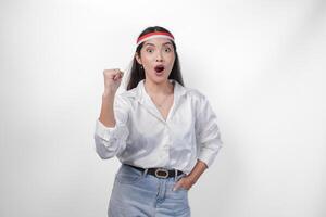 excité Jeune asiatique femme portant pays drapeau Bandeau et serrant mains tandis que célébrer indonésien indépendance journée isolé sur blanc Contexte photo