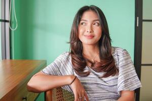 portrait de une magnifique asiatique femme portant robe souriant et séance à une restaurant à avoir petit déjeuner photo