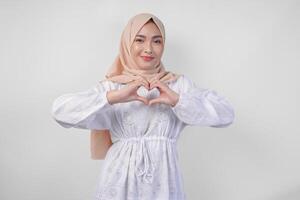 Jeune asiatique musulman femme dans blanc robe et hijab fabrication une cœur l'amour forme geste avec mains dans divers pose, isolé sur blanc Contexte photo