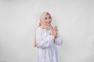 magnifique asiatique musulman femme portant blanc robe et hijab souriant tandis que Faire formel Bienvenue ou salutation geste, permanent plus de isolé blanc Contexte photo