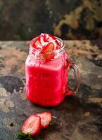 fraise Milk-shake servi dans pot isolé sur foncé Contexte côté vue de en bonne santé boisson photo