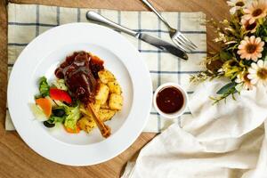 agneau Osso Buco ou osso buco agneau jarrets avec pomme de terre, plonger, couteau, fourchette et salade servi sur assiette isolé sur serviette de table Haut vue de Viande nourriture photo