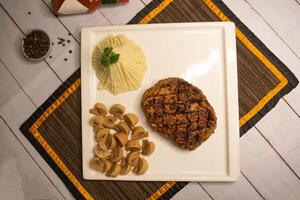 Signature grillé nervure œil du boeuf steak avec champignon, plonger, noir poivre et Ail Chili sauce servi dans plat isolé sur serviette de table Haut vue sur en bois table italien nourriture photo