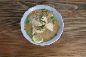 orzo soupe avec poulet, citron vert tranche et coriandre servi dans bol isolé sur en bois table Haut vue de arabe nourriture photo