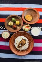 khuder Bah, Hilsa khichuri combo avec salade, aubergine, Borhani et chui pitha servi dans plat isolé sur tapis Haut vue de Indien et bangladeshi nourriture photo