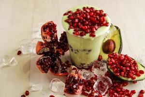 Avocat smoothie avec Grenade des graines servi dans jetable verre isolé sur table côté vue de en bonne santé boisson photo