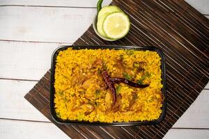 achari poulet khichuri biryani riz Pulao avec concombre et citron tranche servi dans plat isolé sur en bois table Haut vue de bangladeshi et Indien épicé le déjeuner nourriture photo