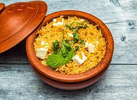 paneer biryani riz servi dans Pot en terre cuite plat isolé sur en bois table Haut vue de Indien épicé nourriture photo