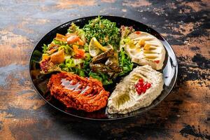 mezze plat ou mezzé Hoummous, vigne feuilles, taboulé, baba ganousch, citron, mutabal servi dans plat isolé sur Contexte Haut vue de arabe nourriture photo