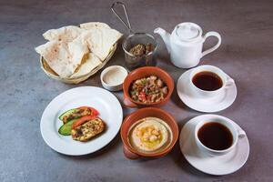 Bahreïn petit déjeuner avec Hoummous, haricots, pain, café servi dans plat isolé sur gris Contexte Haut vue de Bahreïn nourriture photo