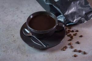 chaud americano portion dans café tasse avec cuillère et des haricots côté vue sur gris Contexte photo