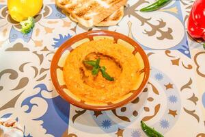 épicé Hoummous avec Chili, cloche poivre, citron et Pita pain servi dans plat isolé sur table Haut vue de arabe nourriture photo