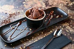 Chocolat gelato avec la glace crème, blanc Chocolat ébrécher, et cuillère servi dans tasse isolé sur foncé Contexte fermer Haut vue de café cuit dessert nourriture photo