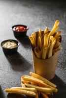 français frites seau avec tremper sauce isolé sur foncé gris Contexte côté vue de vite nourriture photo