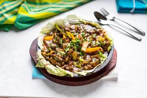 Viande grésillant tomate et vert oignon servi dans plat isolé sur table Haut vue de arabe nourriture photo