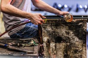 Gros plan des mains de l'homme travaillant sur un morceau de verre soufflé photo