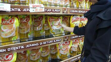 une femme choix cuisine pétrole sur une afficher étagère à une supermarché photo