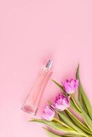 luxe verre bouteille de aux femmes parfum ou cosmétique vaporisateur sur rose Contexte avec printemps fleurs. parfum et beauté concept. verticale vue photo