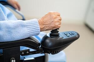 asiatique Sénior femme patient sur électrique fauteuil roulant avec manette et éloigné contrôle à hôpital, en bonne santé fort médical concept. photo