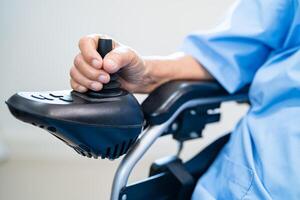 asiatique Sénior femme patient sur électrique fauteuil roulant avec éloigné contrôle à hôpital, en bonne santé fort médical concept. photo