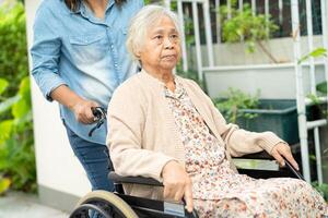 soignant Aidez-moi et se soucier asiatique Sénior femme patient séance sur fauteuil roulant à rampe dans allaitement hôpital, en bonne santé fort médical. photo