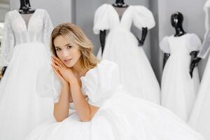 jolie Jeune femme est choisir une mariage robe dans le magasin. le future mariée est portant une mariage robe pour raccord photo