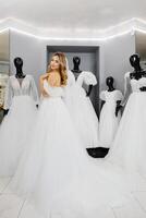 jolie Jeune femme est choisir une mariage robe dans le magasin. le future mariée est portant une mariage robe pour raccord photo