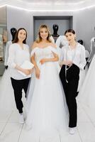 le future mariée choisit une robe pour le mariage. une couturière assistant est raccord une robe pour le la mariée photo