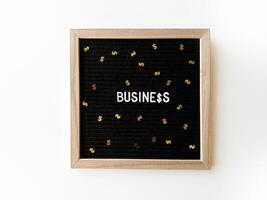 noir lettre planche avec orthographié mot affaires et dollar signe confettis. affaires gains concept. finance. photo