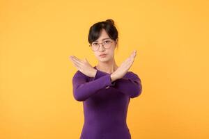 portrait asiatique magnifique Jeune femme 30s malheureux porter violet chemise en portant deux traverser bras dire non X signe, studio coup isolé Jaune arrière-plan, femelle modèle pose rejeter geste avec copie espace photo