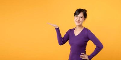 photo de 30s asiatique femme portant violet chemise content positif sourire spectacle mains produit promo offre vente isolé plus de Jaune Couleur Contexte.