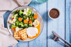 mélanger de bouilli légumes, poché Oeuf et gaufre pain grillé sur une assiette sur le table Haut vue photo