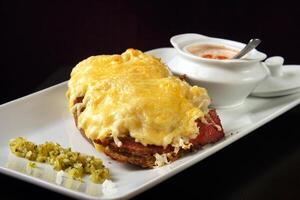 ouvert pastrami sandwich sur assiette avec Gratin fromage et vinaigrette sauce photo