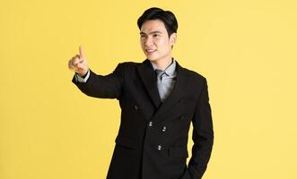 portrait de asiatique Masculin homme d'affaire. portant une costume et posant sur une Jaune Contexte photo