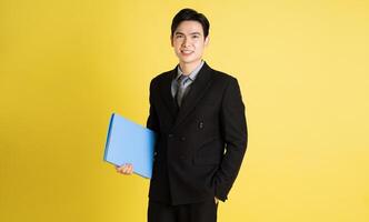 portrait de asiatique Masculin homme d'affaire. portant une costume et posant sur une Jaune Contexte photo